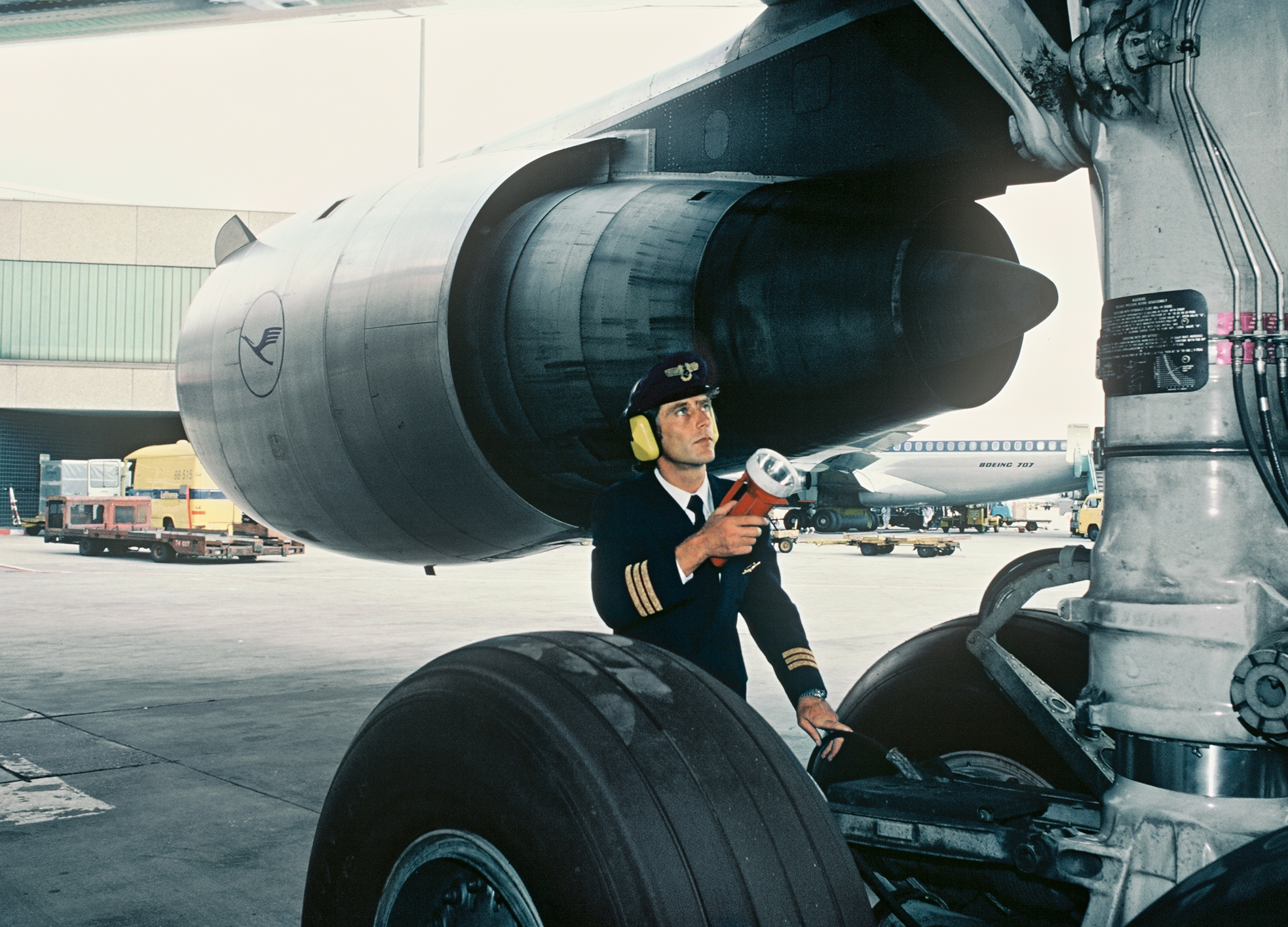 A Lufthansa First Officer checks the aircraft's  exterior in preparation for departure.