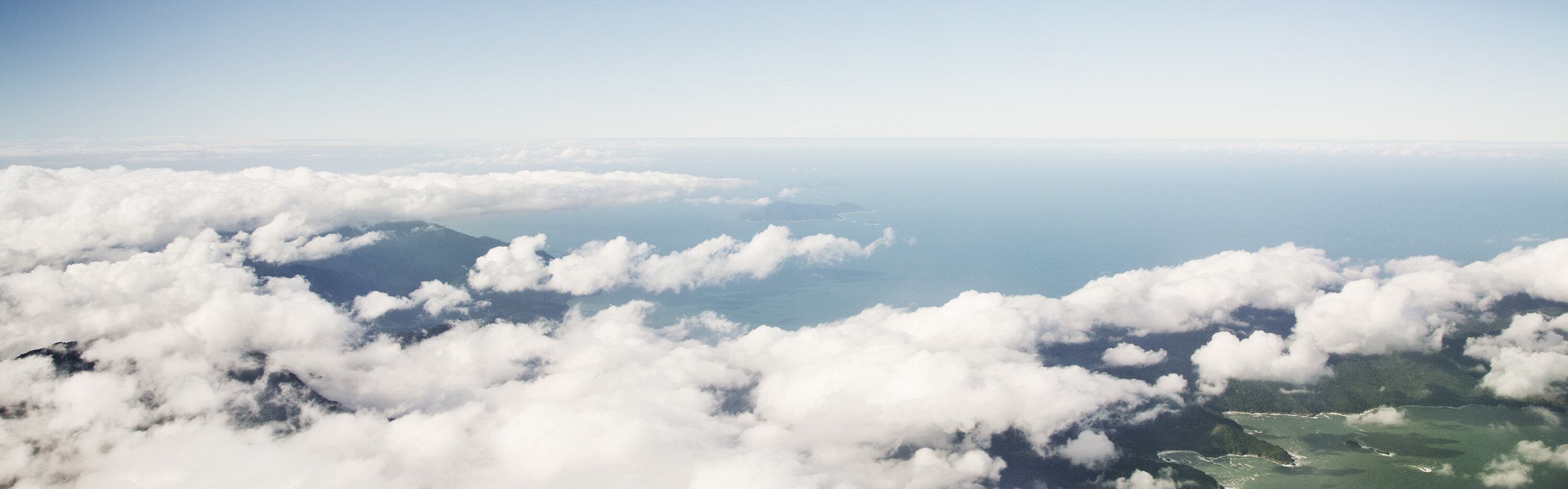 Eine fliegende Boeing 747 über Wolkenformationen mit drunterliegender Küste und Ozean Eine fliegende Boeing 747 über Wolkenformationen mit drunterliegender Küste und Ozean